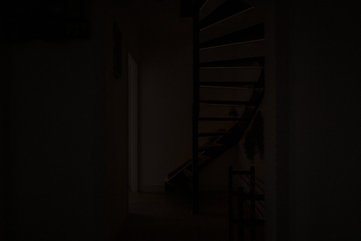 A person climbing the spiral staircase, each tread lighting up as they step on it